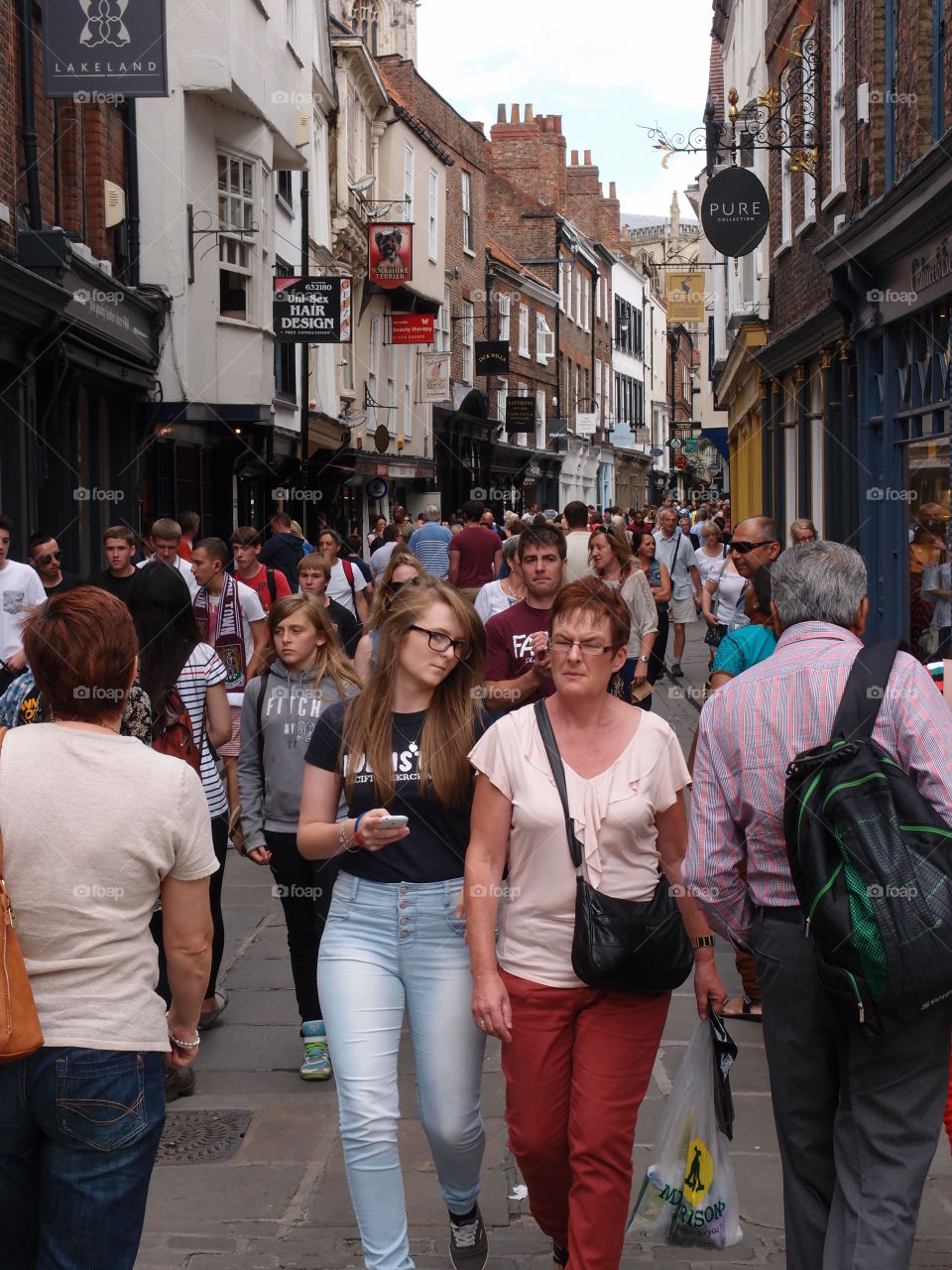 Crowds of people walking through shopping districts in An English town on a sunny summer day. 