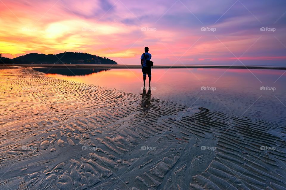 Man standing over the beach watching beautiful sunrise