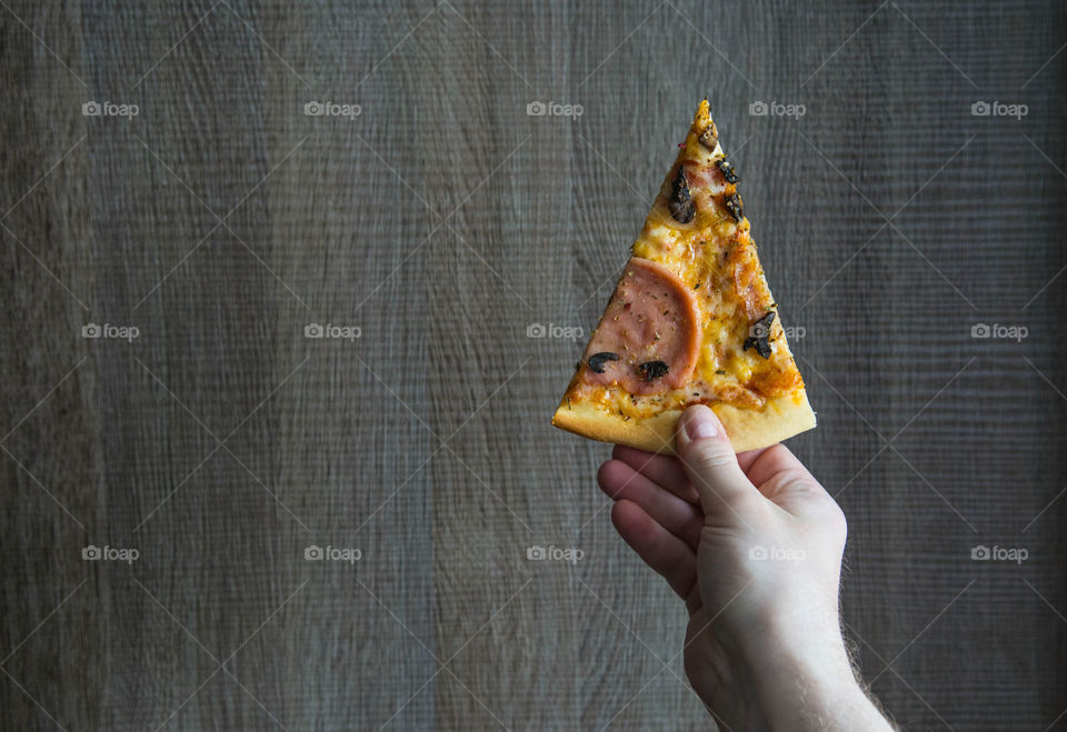 Person holding slice of pizza