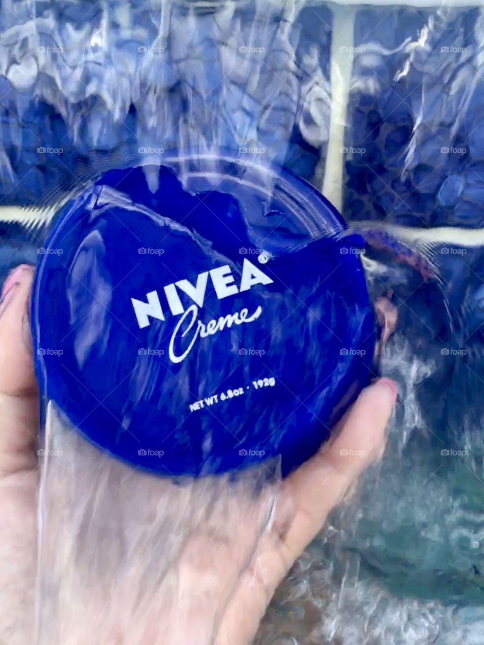 Nivea creme held by hand in waterfall 