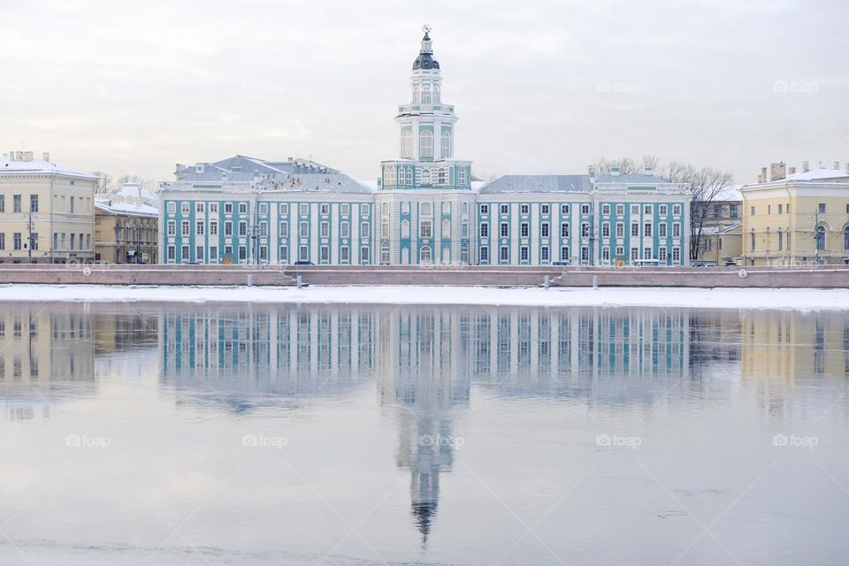 Saint-Petersburg - 10.02.2021: View of the Kunstkamera and its reflection in the thawed Neva River in winter