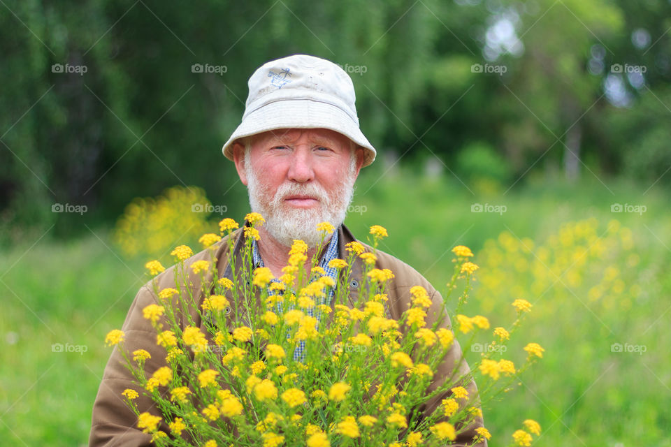 Portrait of senior man holding bunch of yellow flowers