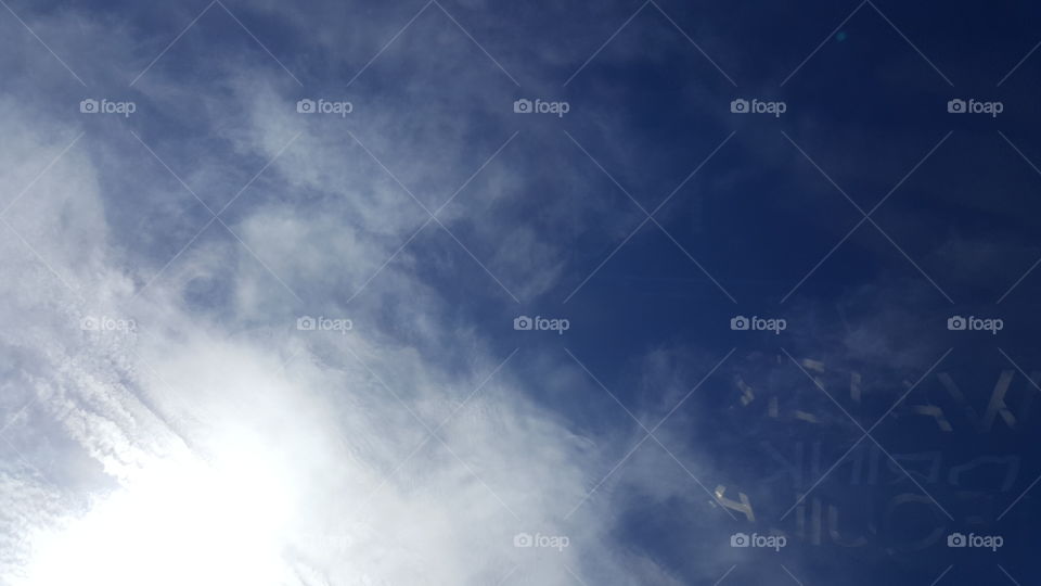 The sun illuminates the clouds in the deep blue sky.