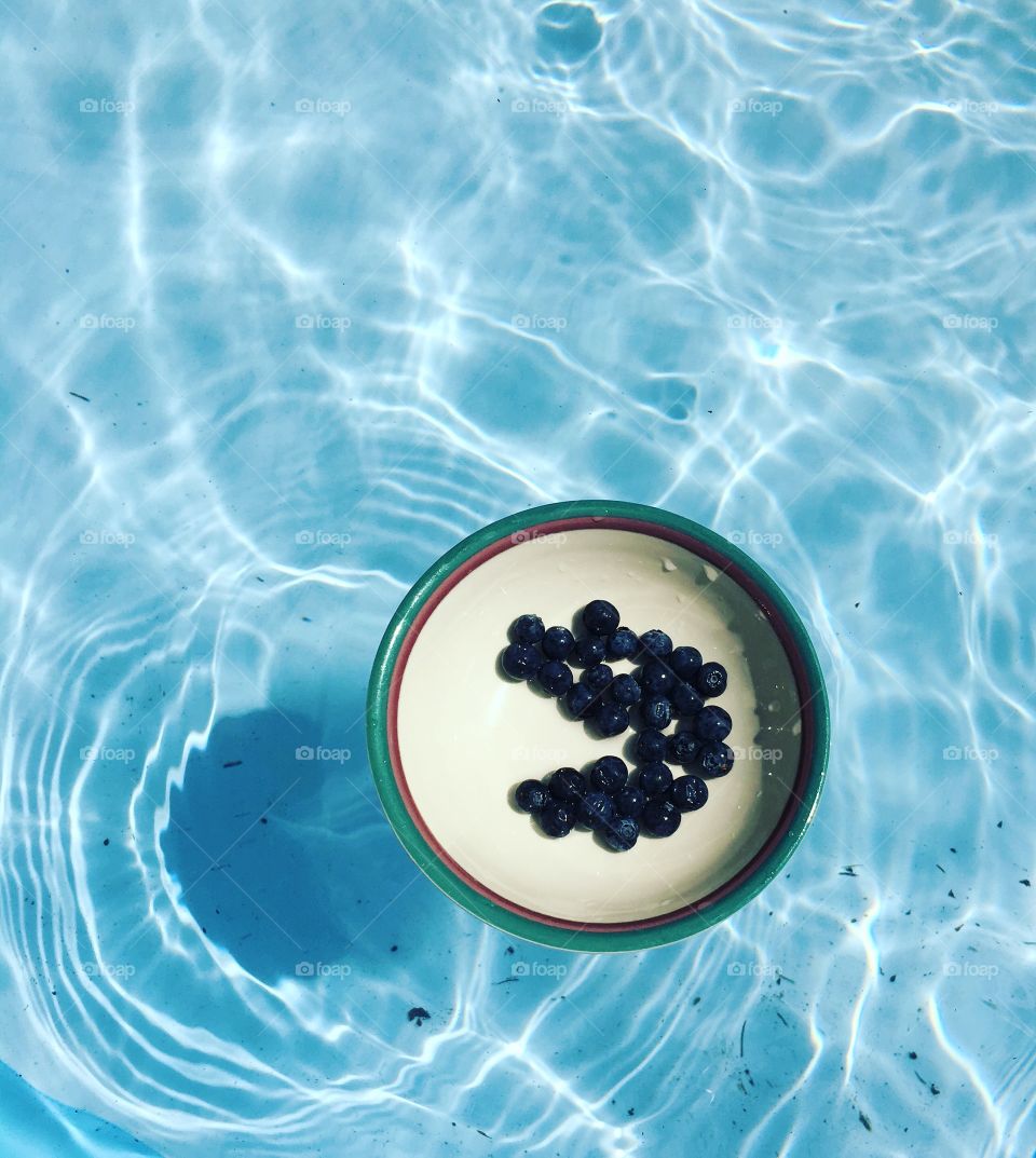 Blueberries in a bowl floating on swimming pool