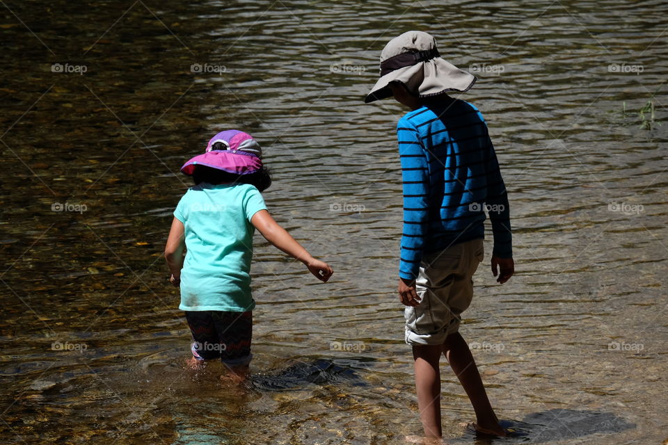 Little friends wading in the water during summer vacation.