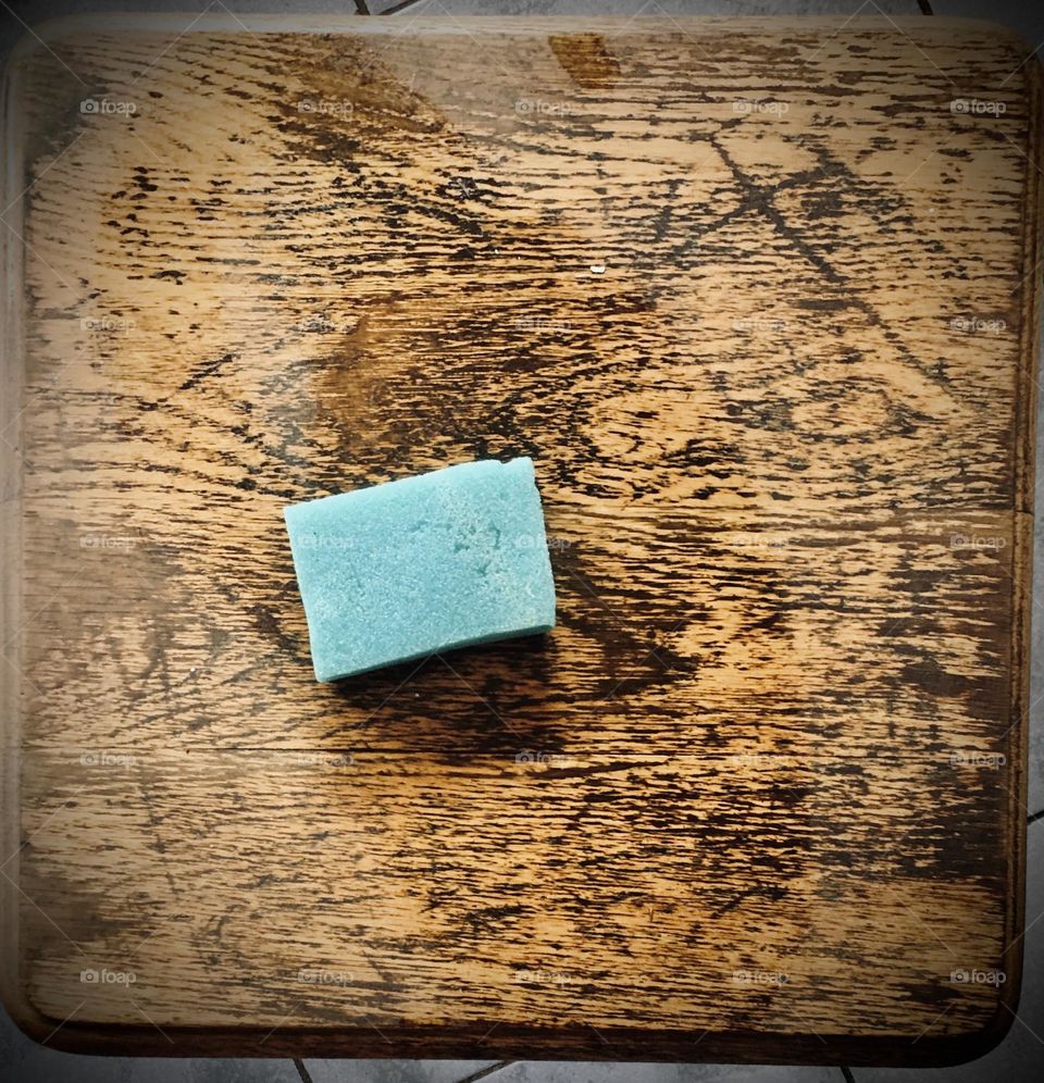 Cleaning an old, dusty wooden side table with a blue sponge 