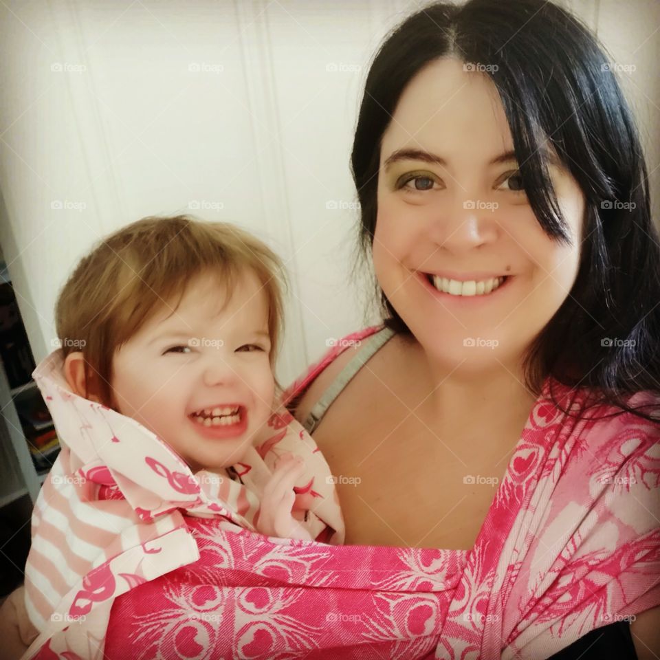 mother and daughter in a babywearing wrap or sling. very pink. happy smiles