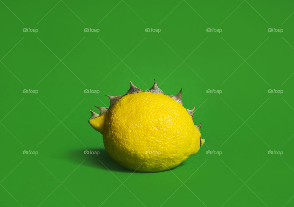 Yellow lemon with spikes on green background