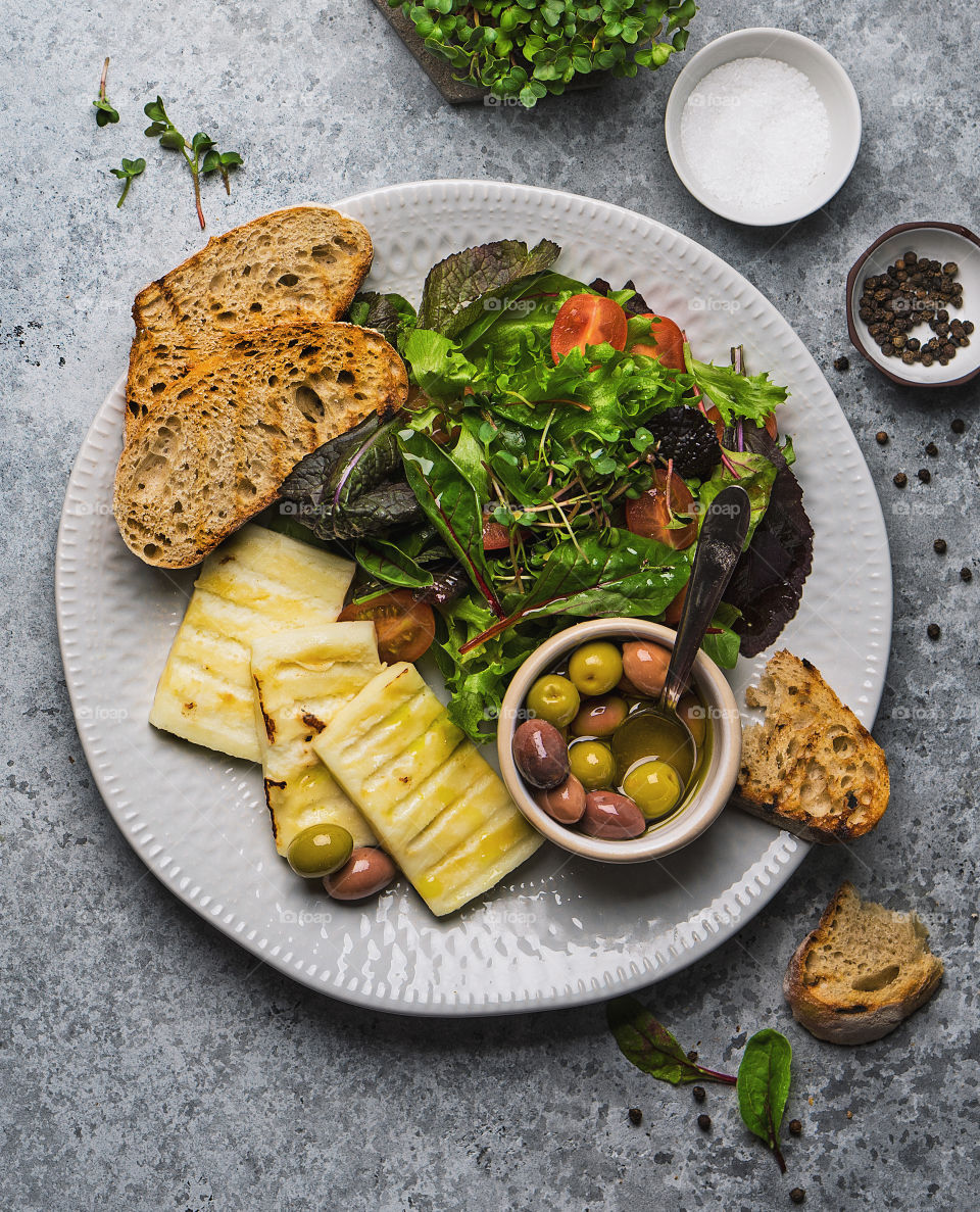 Plate with grilled cheese, salad and olives