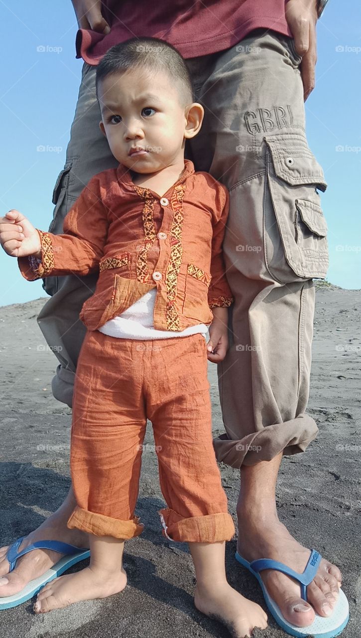 a little boy standing in front of his father