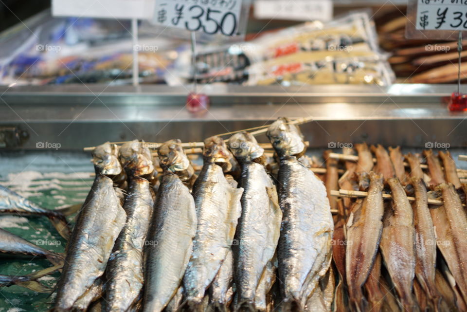 Japanese seafood fish market with whole fishes skewered on display in a coastal town in Hokkaido