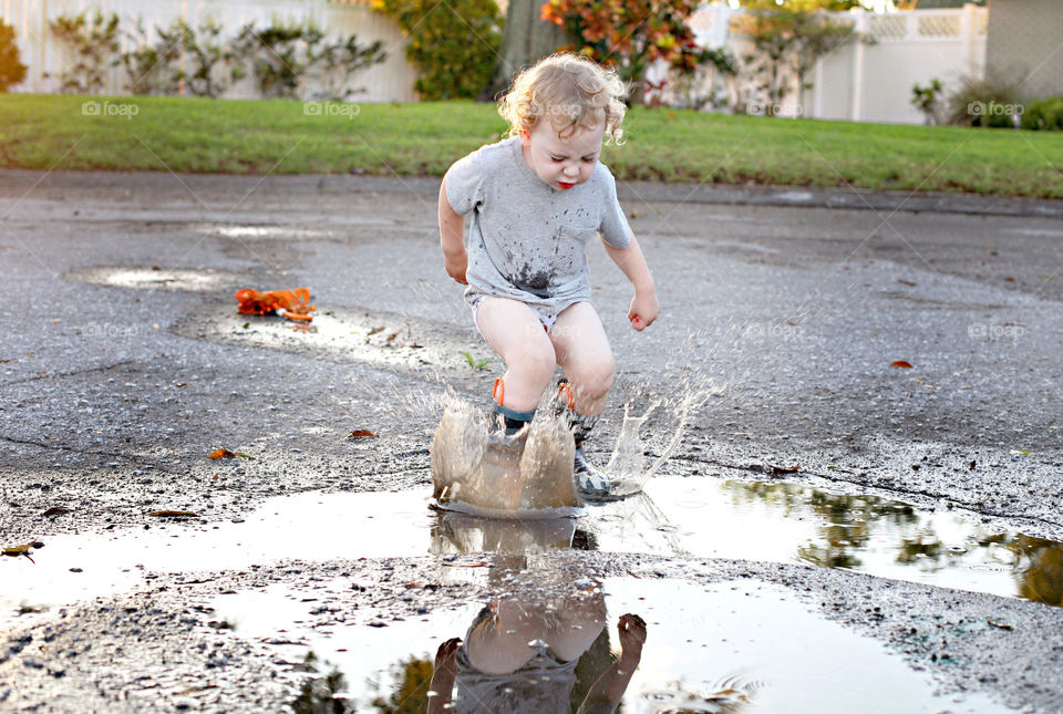 Cute boy splashing water on street