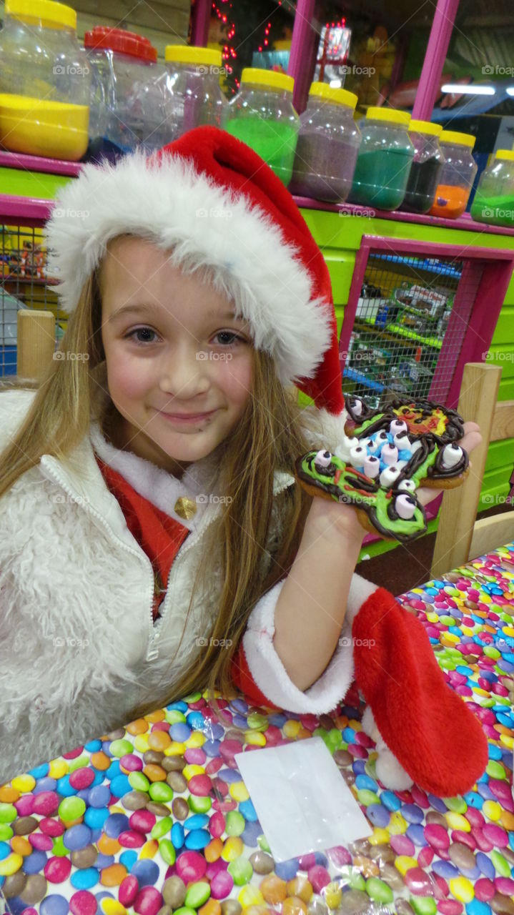 blond pretty girl ith long hair posing with a Christmas festive cookie she has decorated