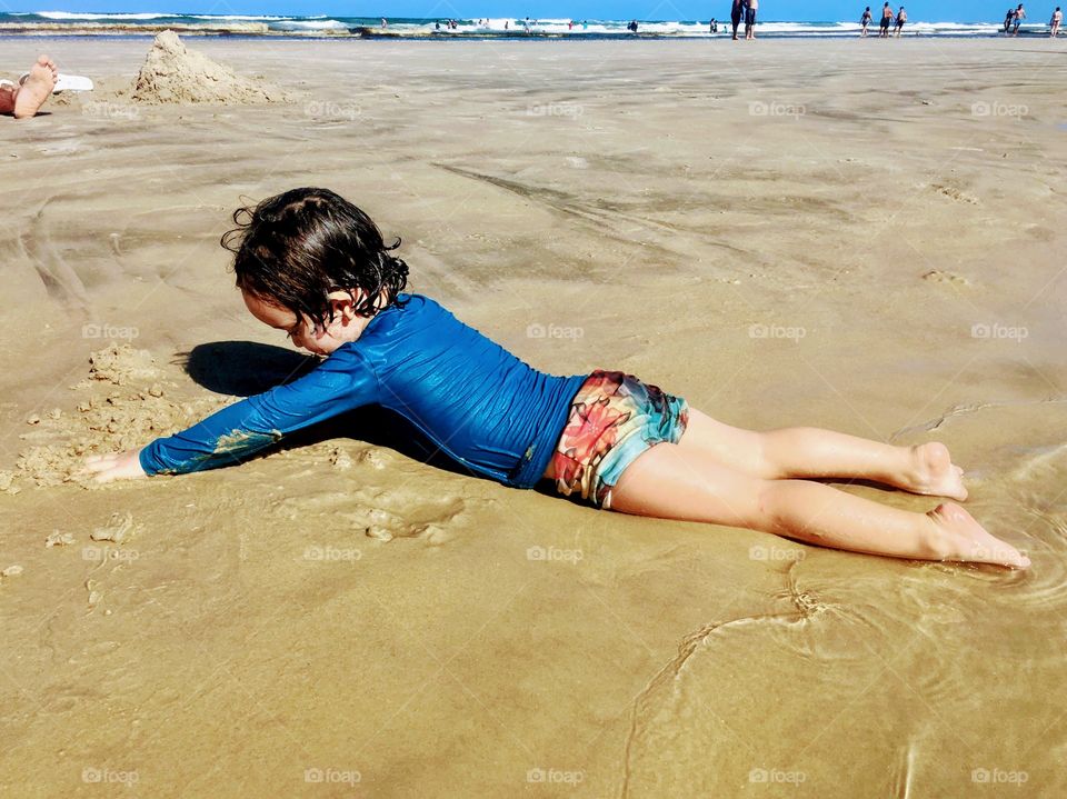 Child playing on beach sand in summer vacation