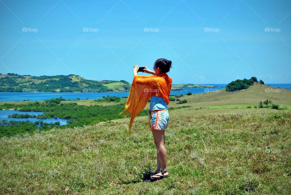 lady holding a camera phone taking a photo of the beautiful scenic view