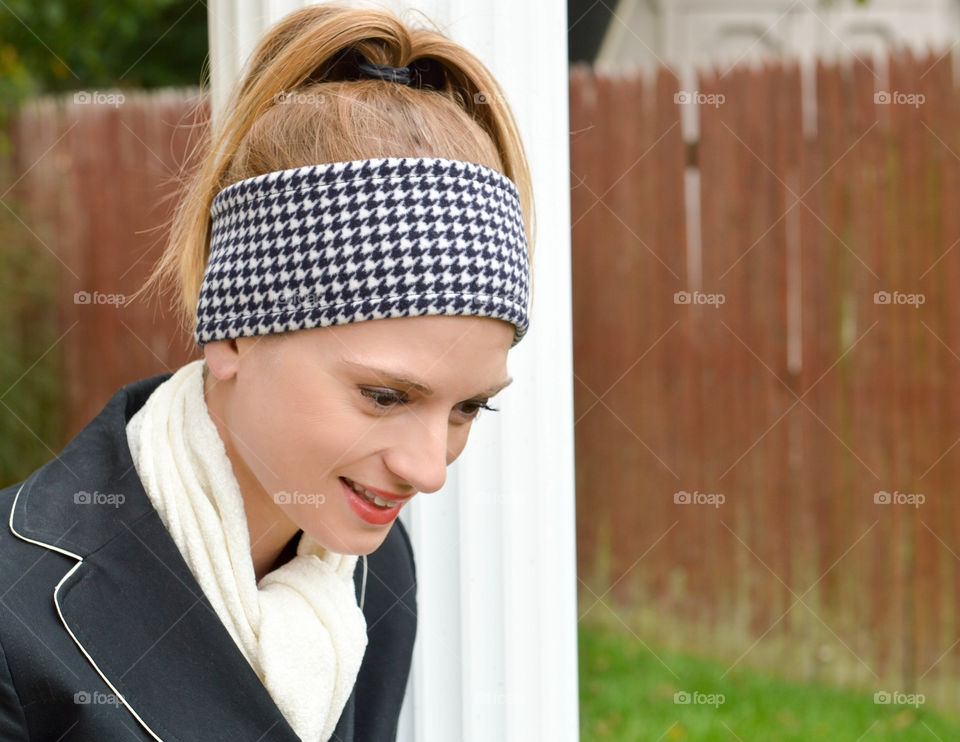 Woman wearing a houndstooth print headband and white scarf outside