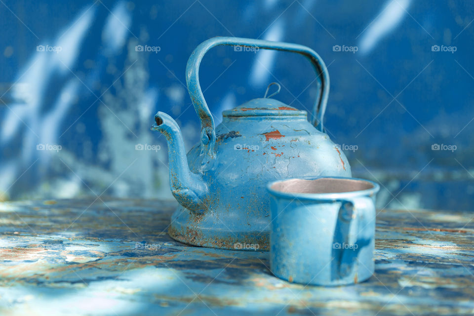 Antuque old blue kettle and tin mug on a table
