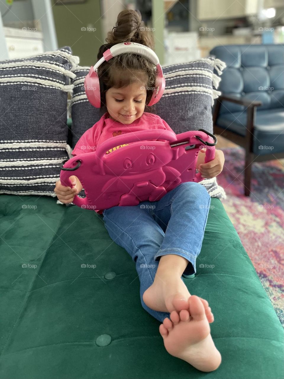 Toddler girl wearing pink with pink accessories, toddler relaxes with technology, toddler in pink, having fun in pink, toddler using iPad and headphones