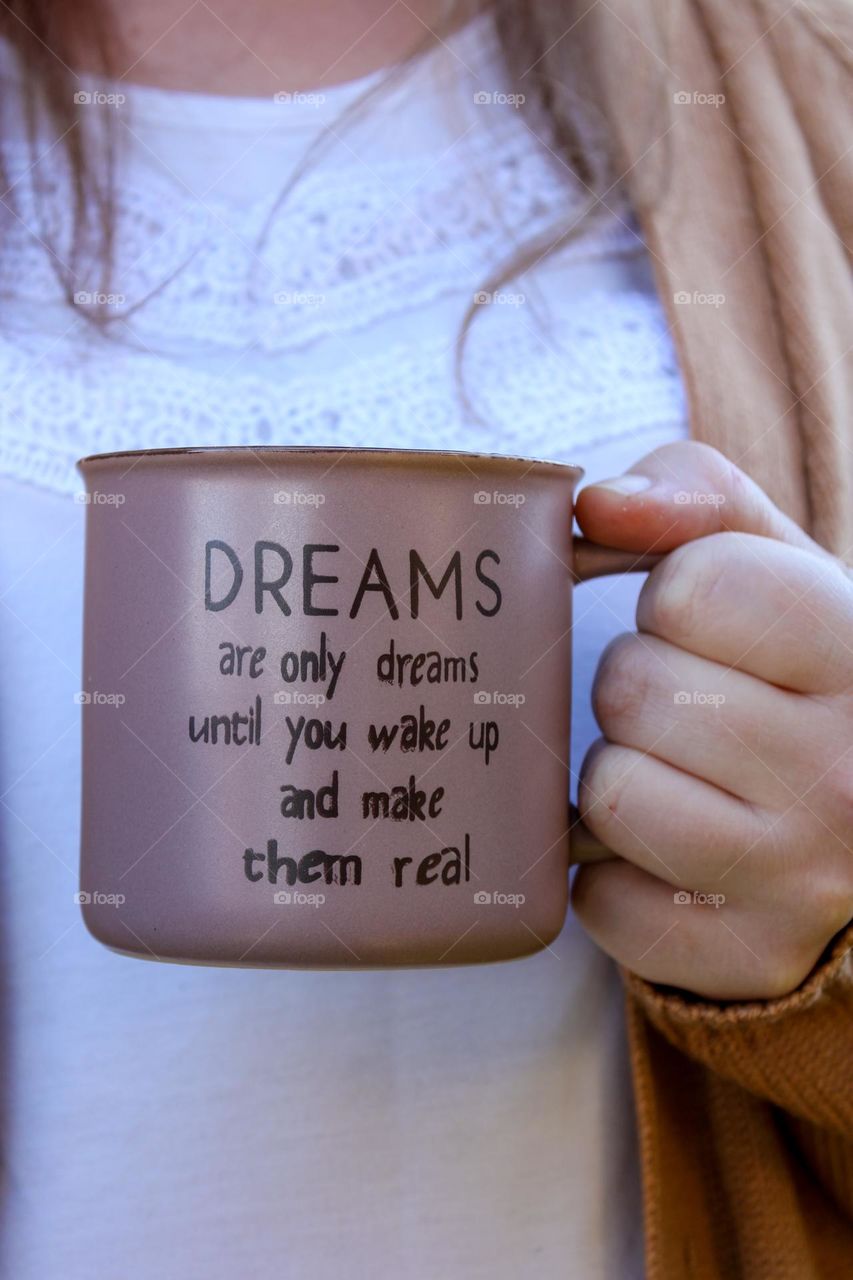 Close up of a hand holding a coffee mug with a motivational quote on