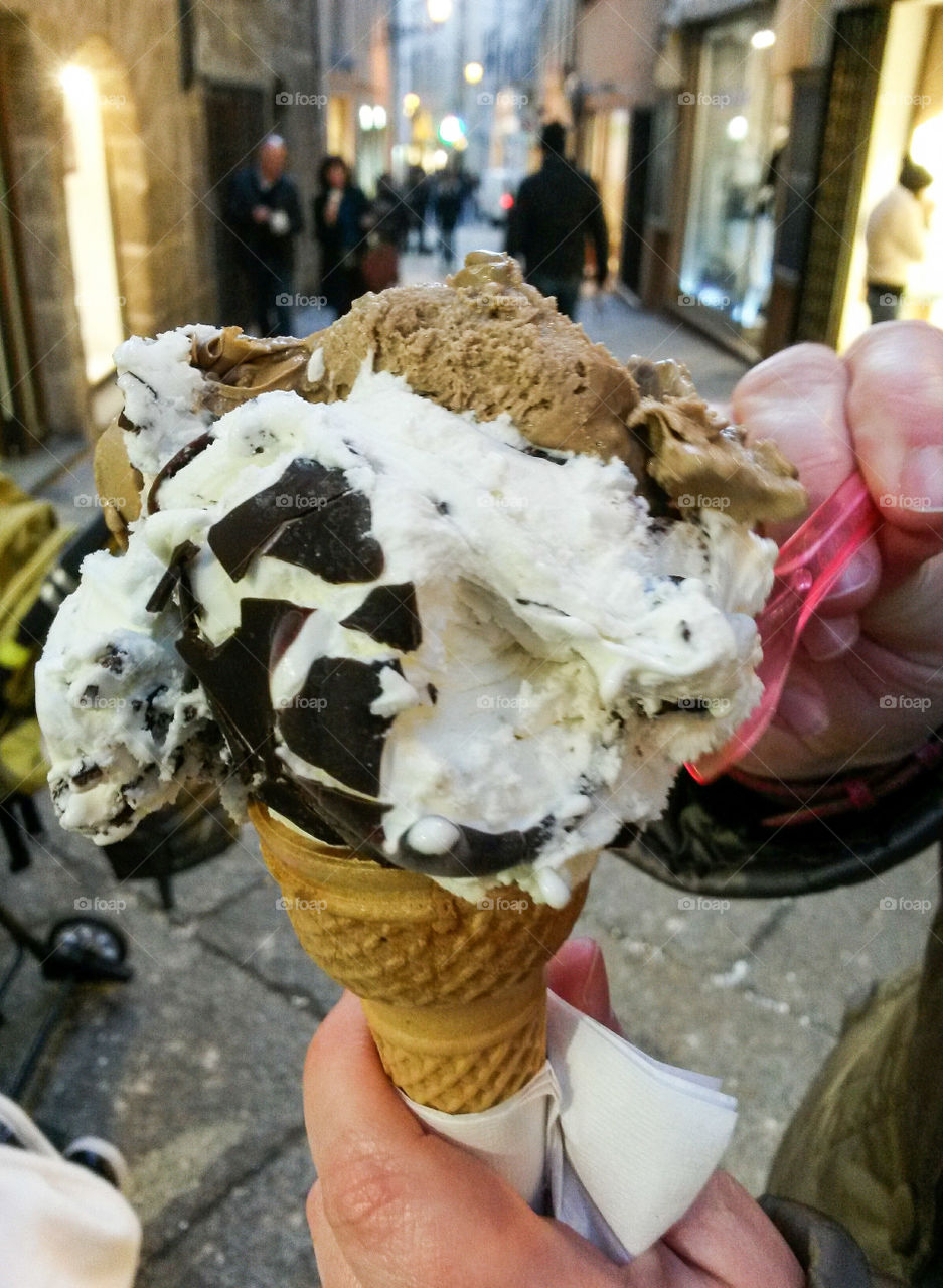 Person hand holding vanilla with chocolate ice cream