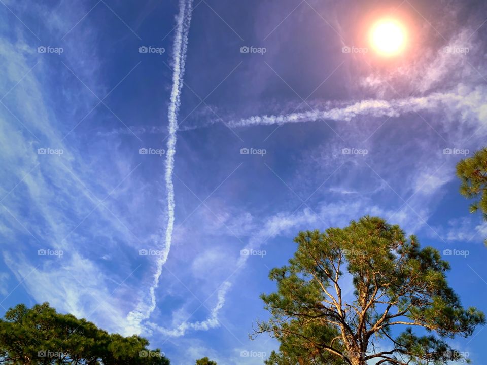 Glowing sun , crystal blue skies and contrails.