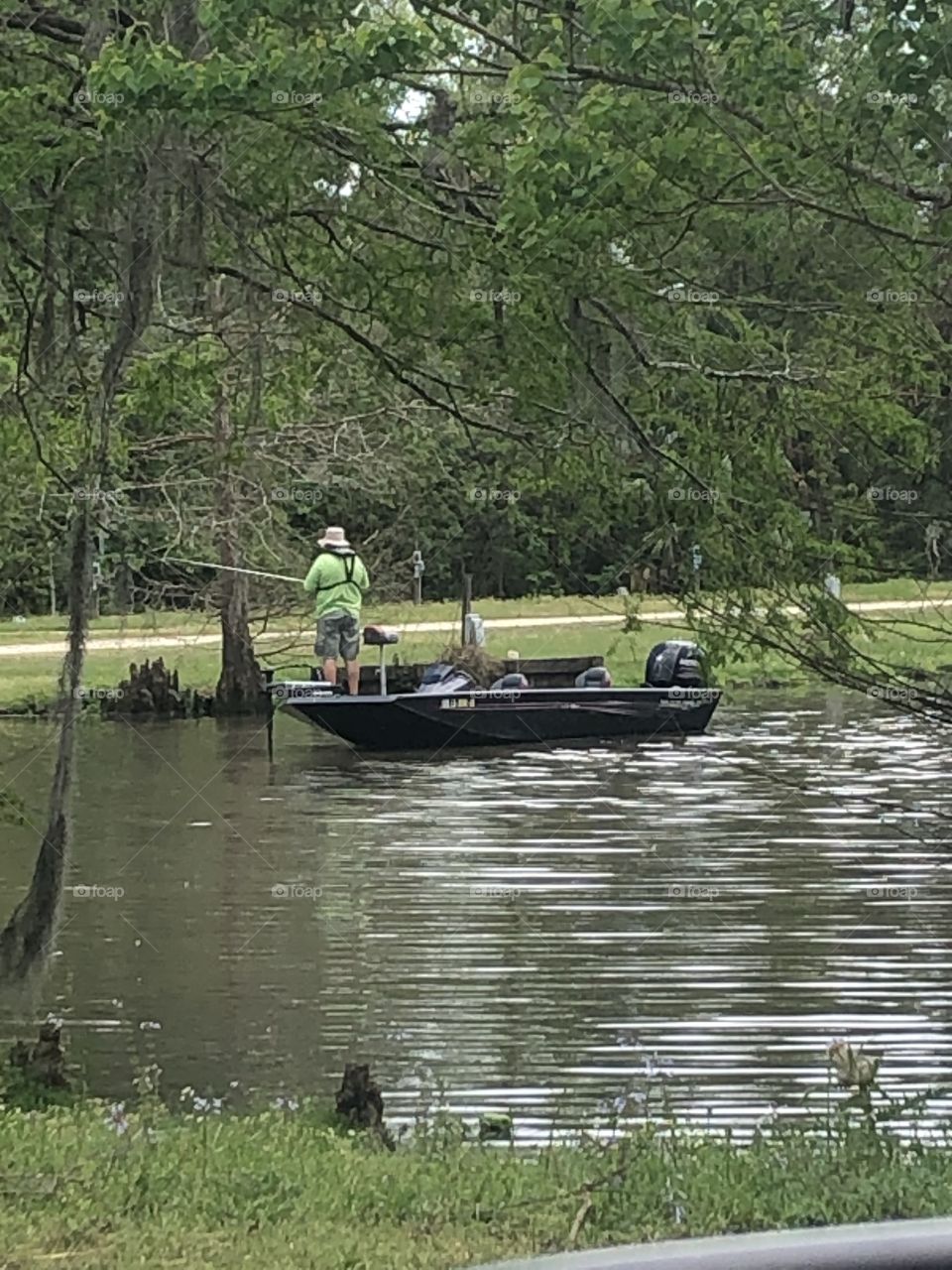 Man in a boat out on the water, fishing on a spring day. 