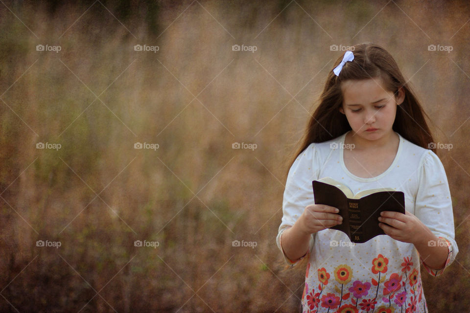 Girl reading bible in the bushy weeds