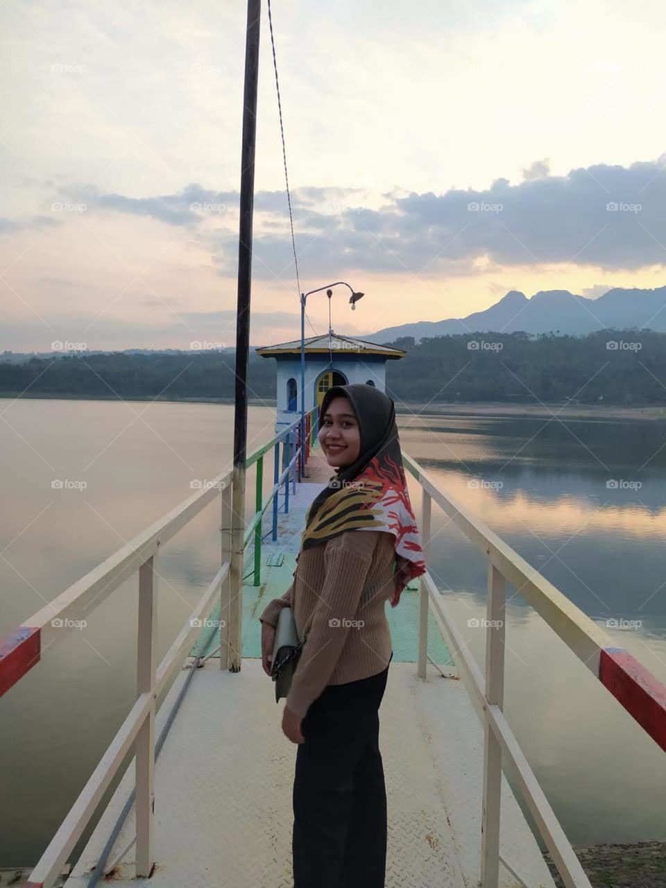 A girl standing on a bridge with mountains in the background