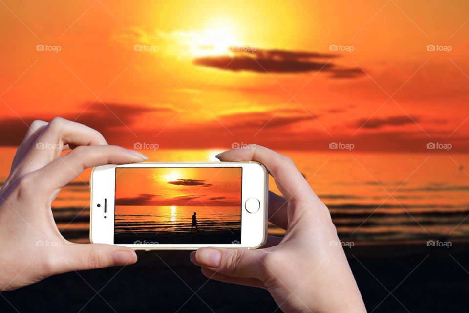 Using my mobile device to take a picture of a sunset on Fort Myers Beach in Florida