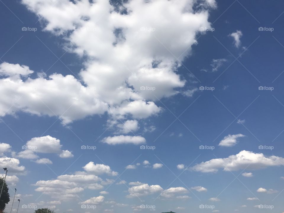 Fluffy clouds scattered across a deep blue sky.