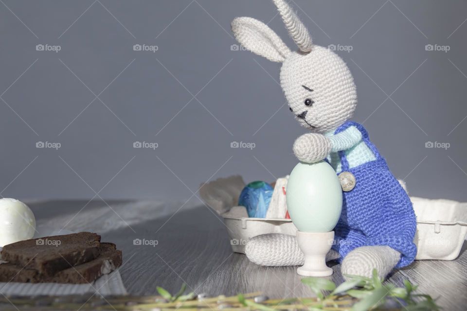 The Easter Bunny is on a wooden surface with painted eggs