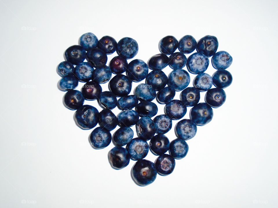 Heart made from blueberries on white background