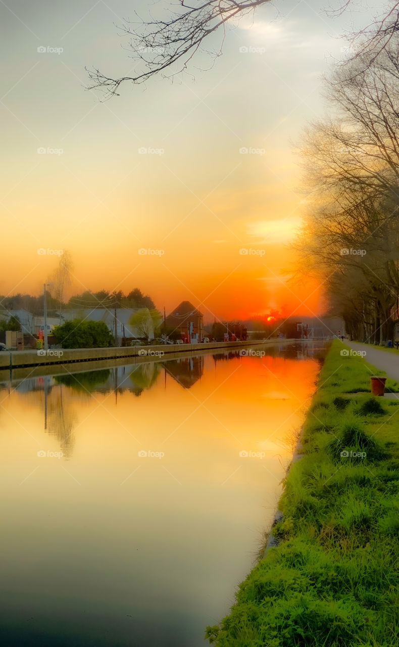 Glowing orange red sunset reflected in the water of the river