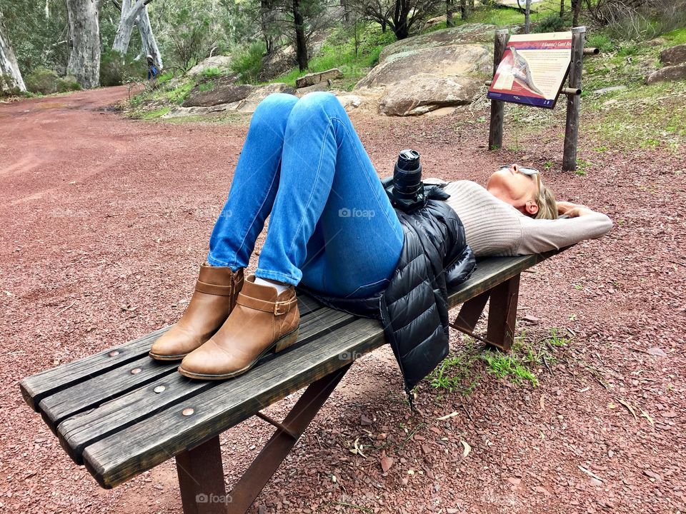 Woman lying on bench with camera