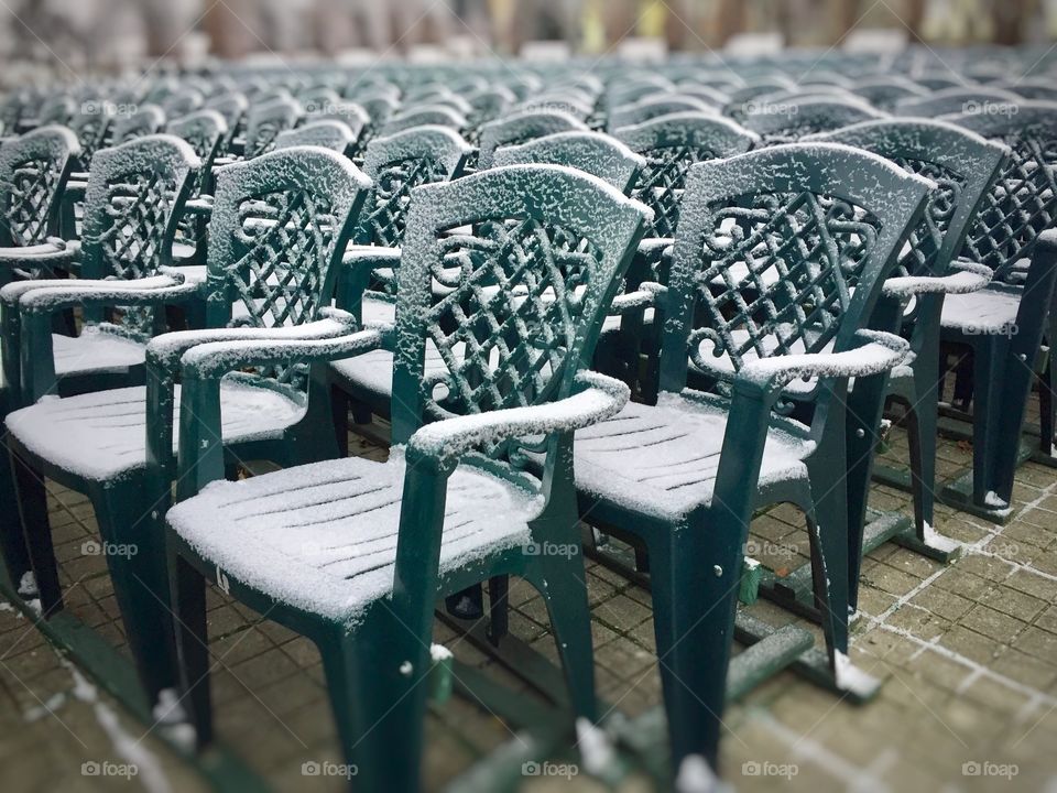 Bunch of green plastic chairs covered in snow 