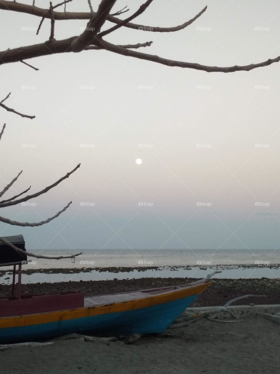 Evening with moon in an island at low tide, view from a fishing beach