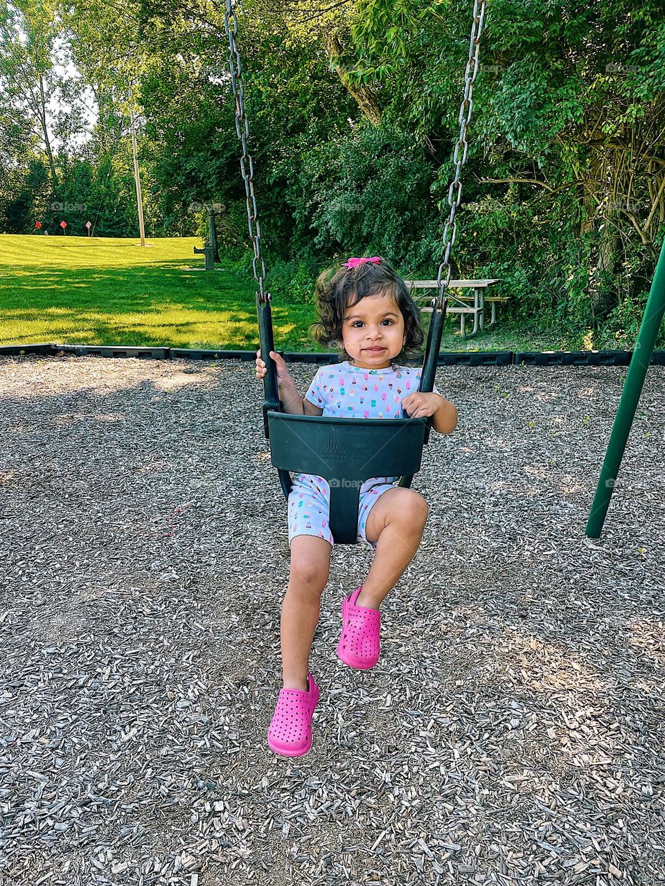 Portrait of a toddler on a swing, toddler girl on a swing, toddler girl at the park having fun, toddler swinging at the park, toddler and mommy time, toddler has fun outside, toddler girl at the park with mommy