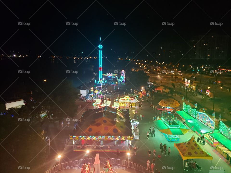 Late night photo taken from the top of a ferris wheel in Barrie, Ontario. Carnival rides and neon lights during the Kempenfest Waterfront Festival.