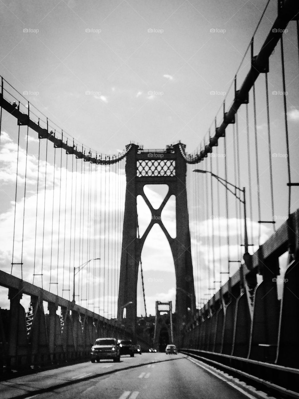 B & W suspension bridge in silhouette from down below 