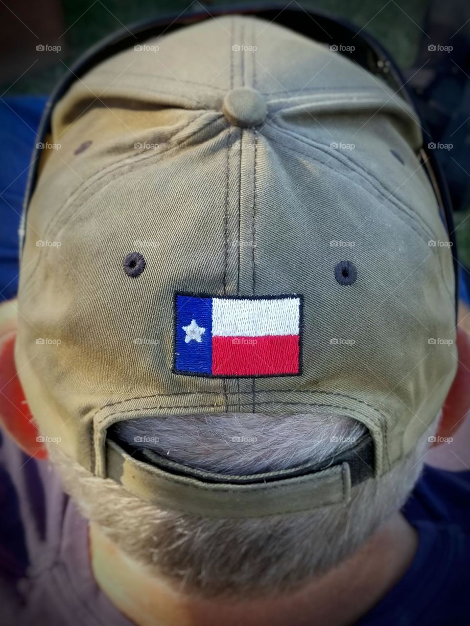 Man wearing a well worn baseball cap with the Texas Flag on the back