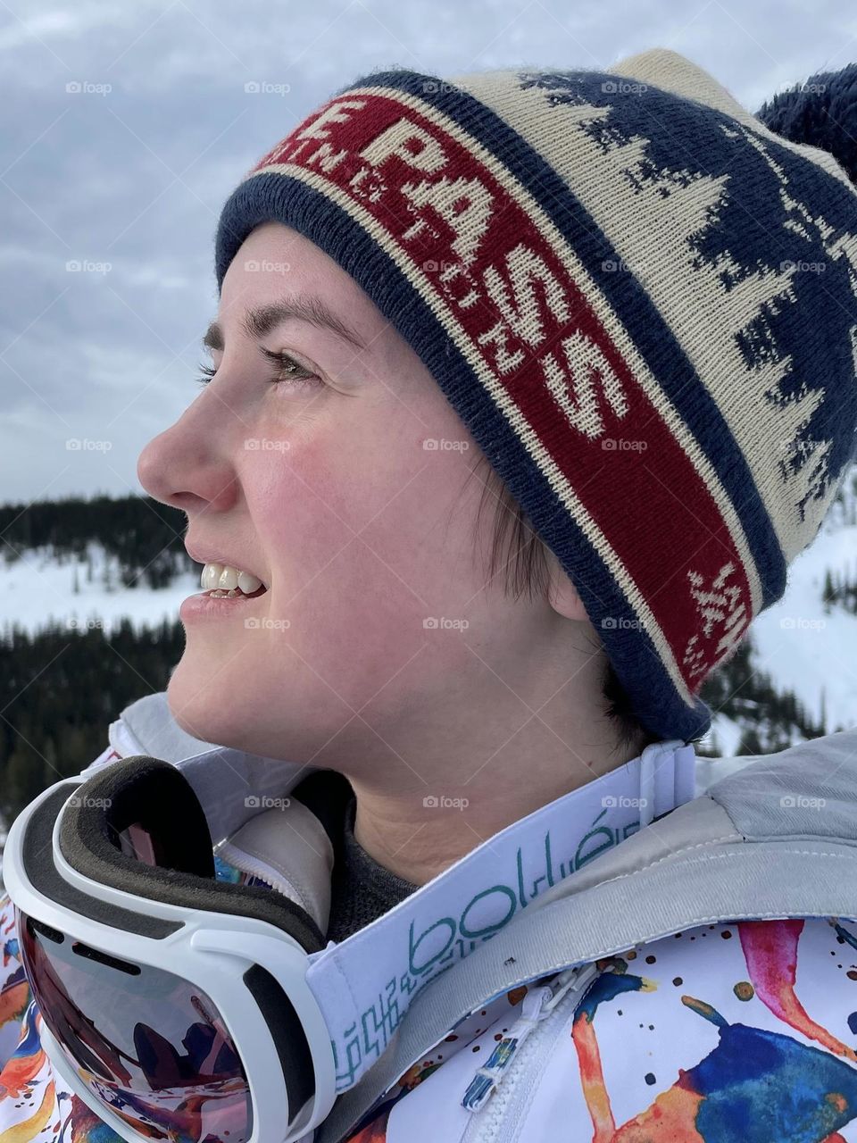 A young woman enjoys a break from snowboarding to take in fresh mountain air on a crisp winter day