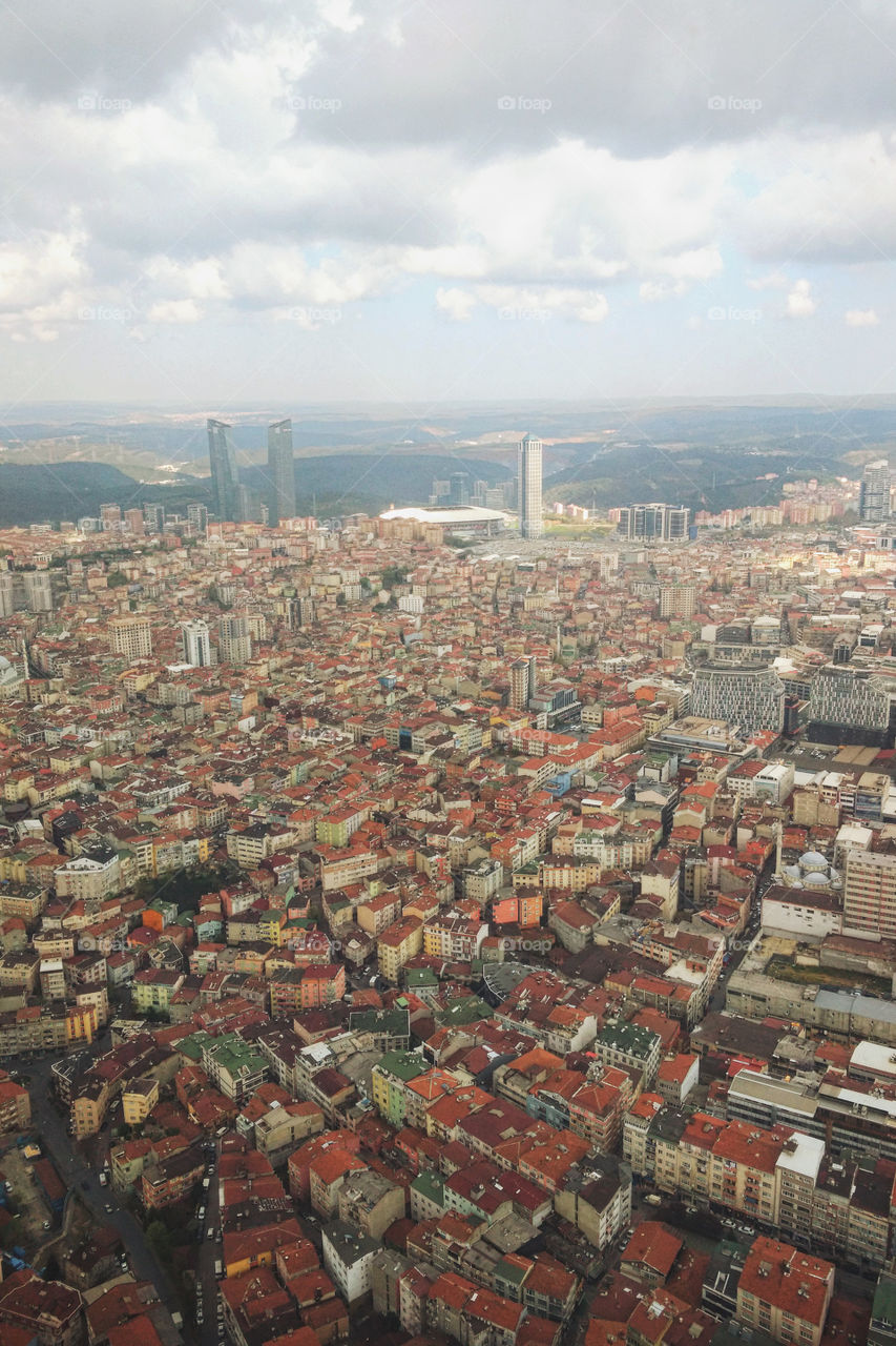 A view from the window of a high-rise building on a multi-million dollar city with roads, avenues, skyscrapers and houses with red roofs.  Urban studies.