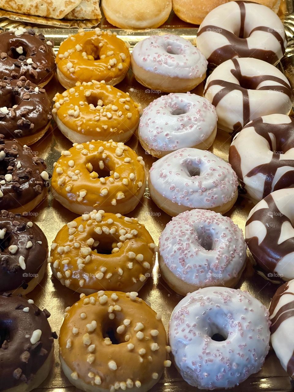 Chocolate, nuts and sugar glazed donuts exposed at a bakery store window 