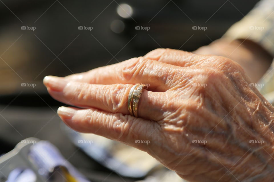 an elderly woman shows off her wedding and engagement rings