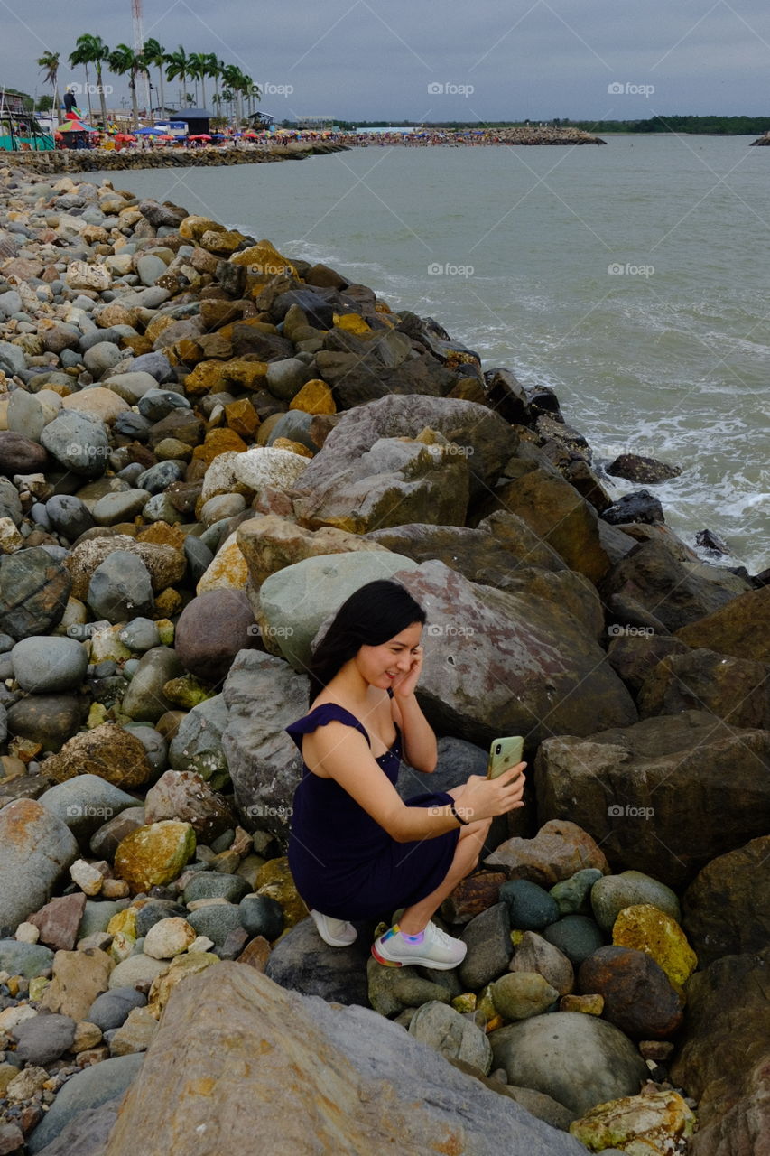 Young woman with cell phone taking a picture at the beach