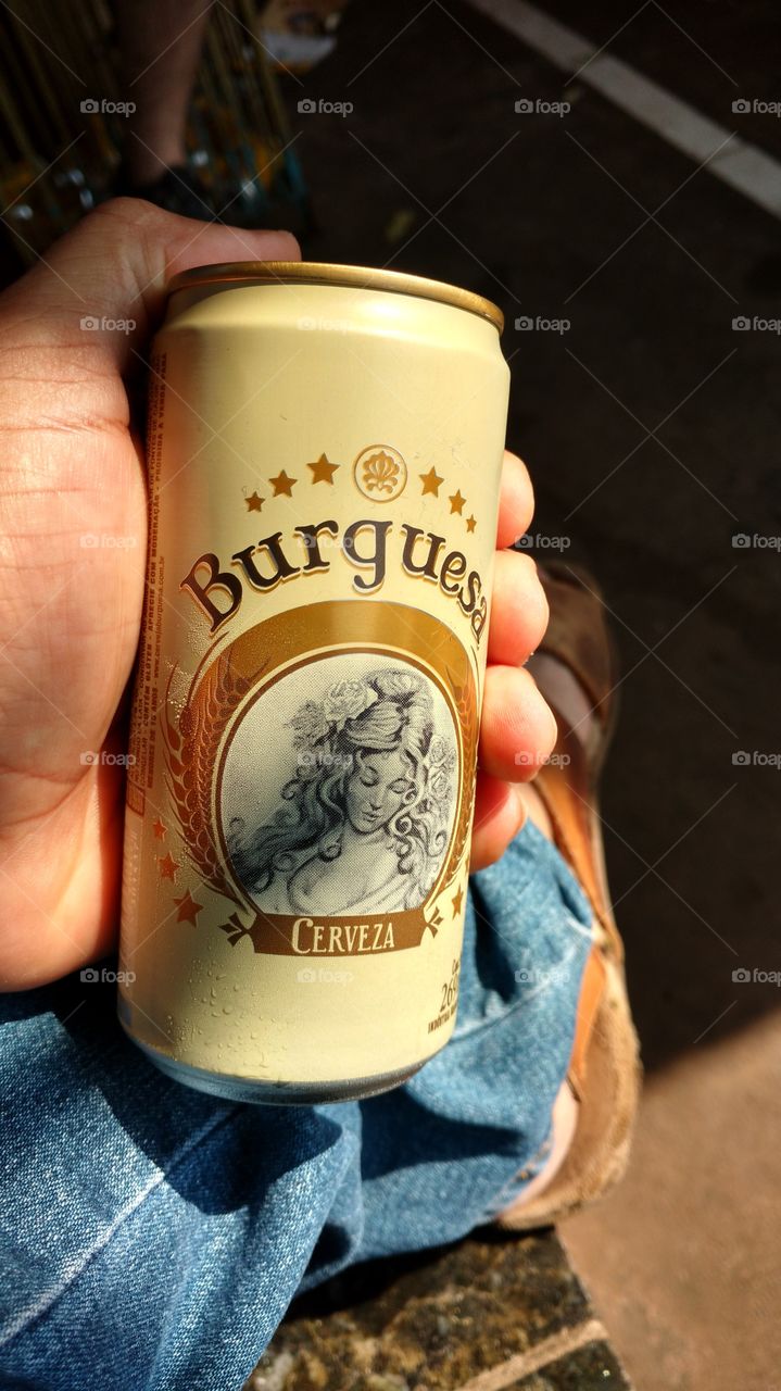 Latinha de cerveja Burguesa, na mão.