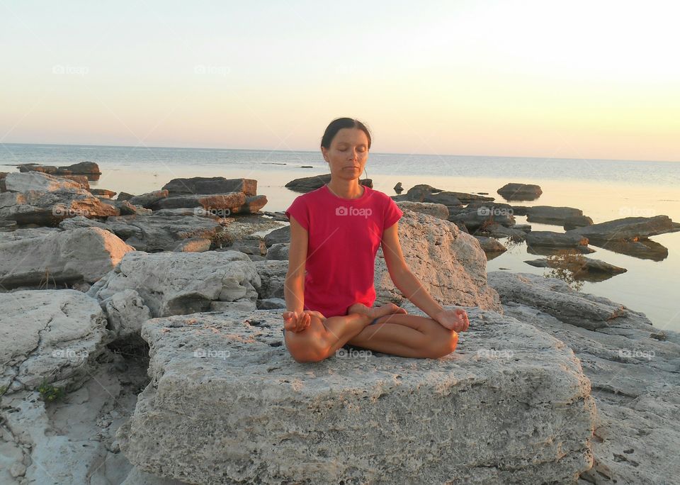 girl meditation on a sunset sea stone shore