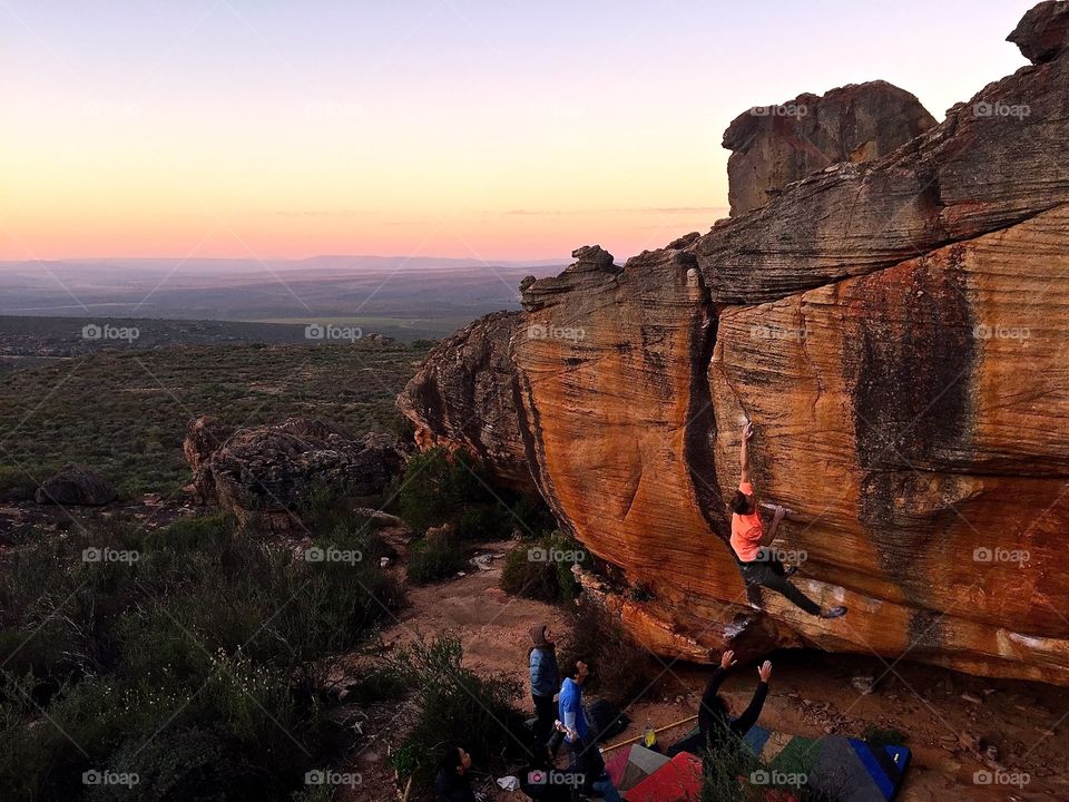 Sunset climbing session. Rock climbers support each other in a boulder in the sassies area of the Rocklands in South Africa at sunset. 