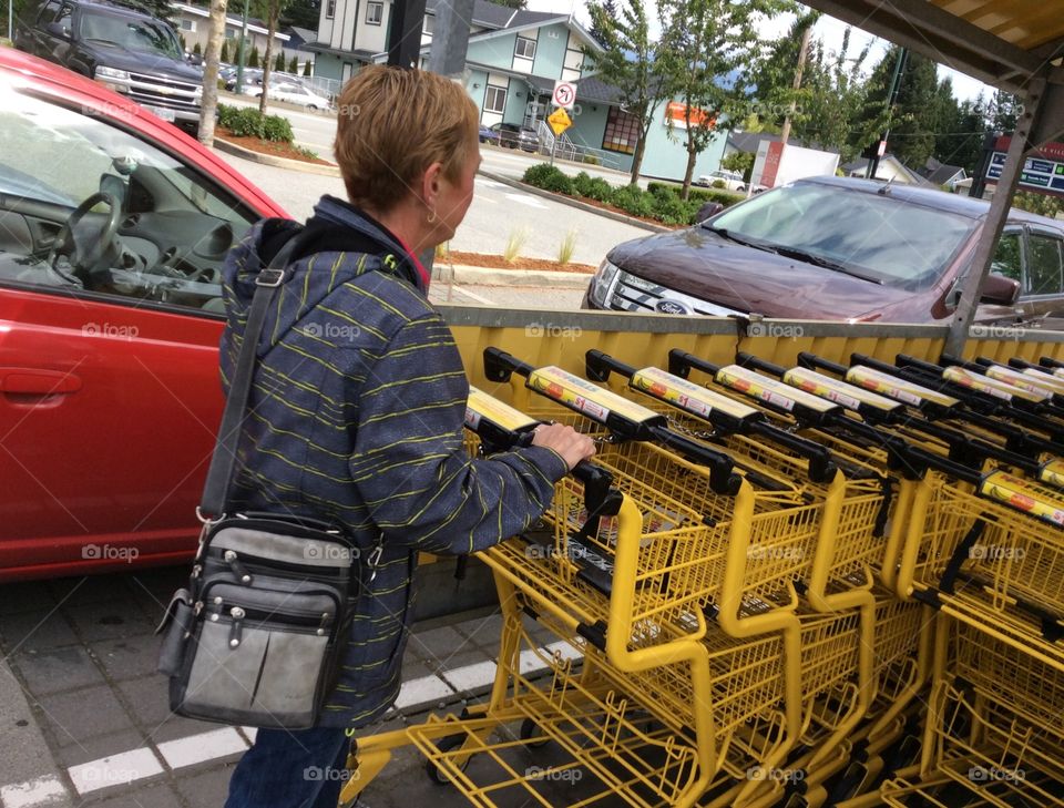 Yellow shopping carts trolleys. Shopper returning yellow shopping cart