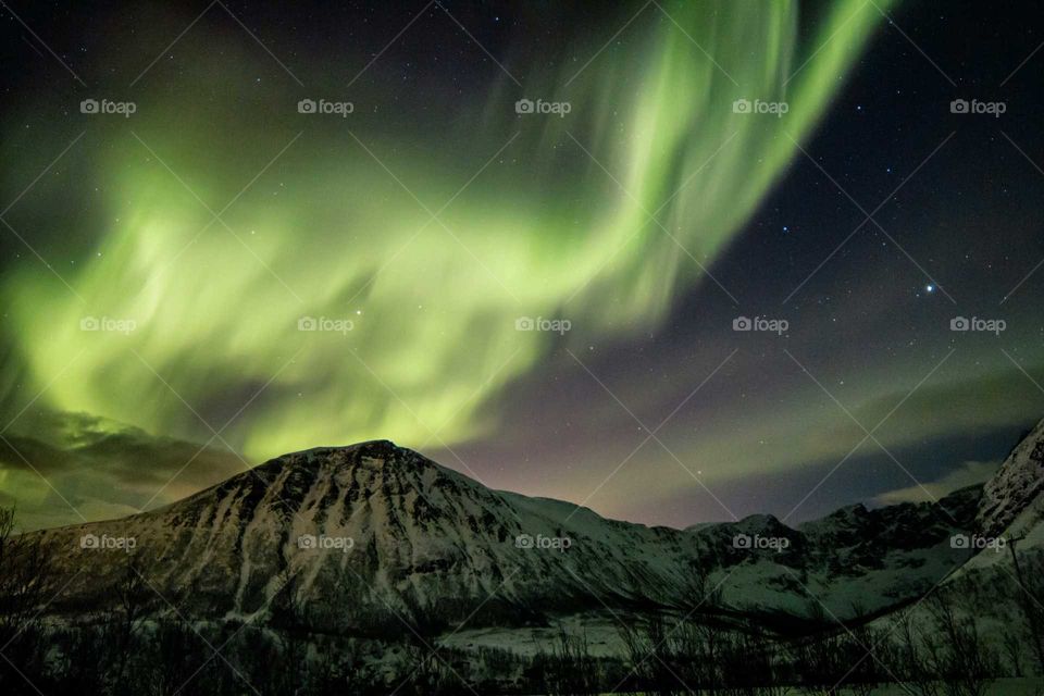 Aurora borealis over mountain against sky